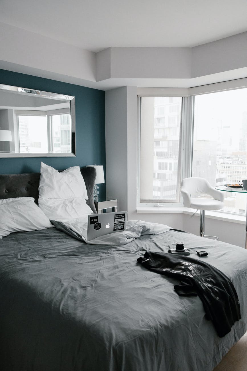 a gray bedroom with laptop on the bed