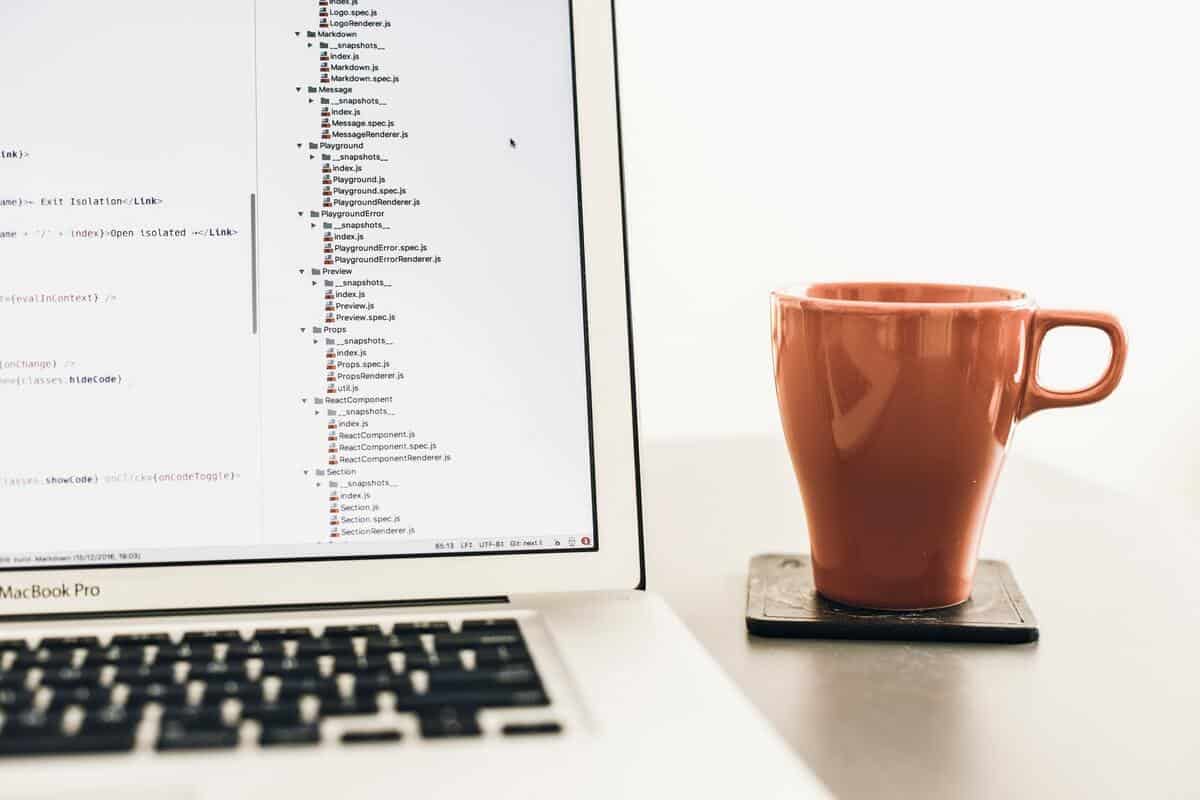 a laptop displaying code with coffee mug next to it