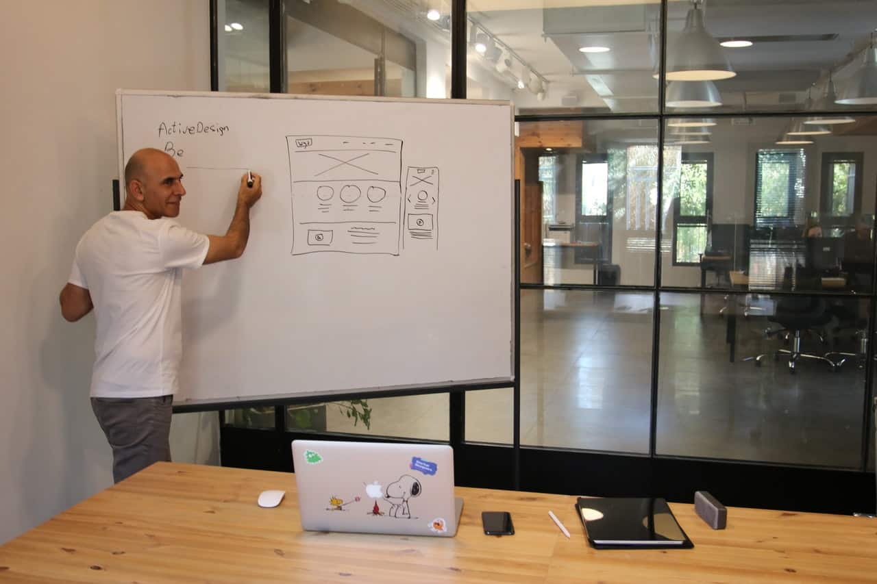 a man drawing and explaining UI design on whiteboard