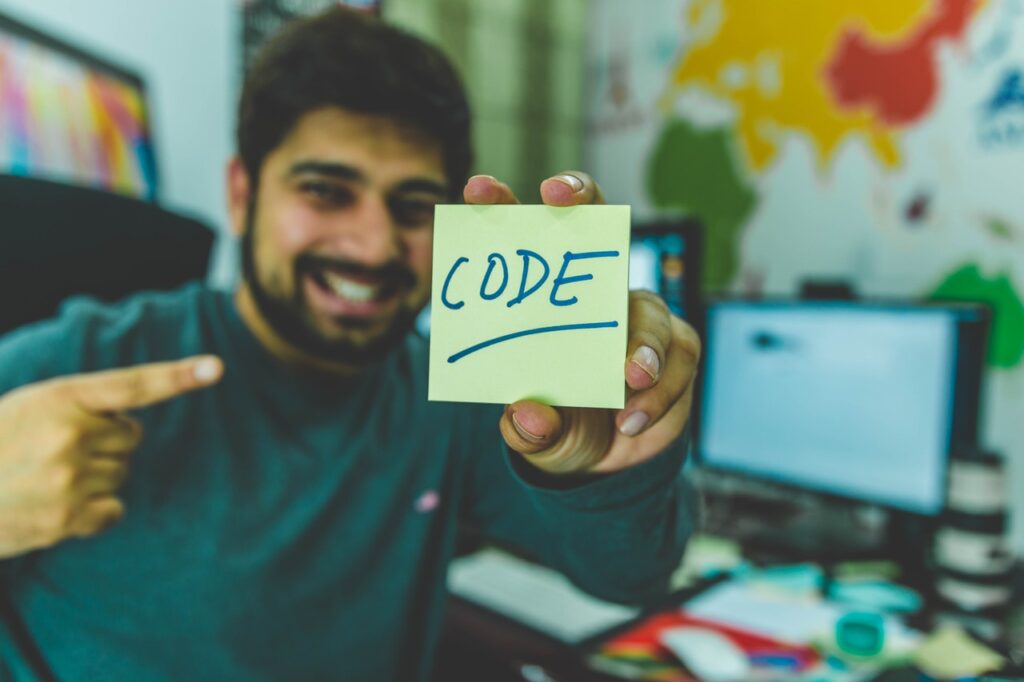 a happy man holding a sticky note with the word code written on it