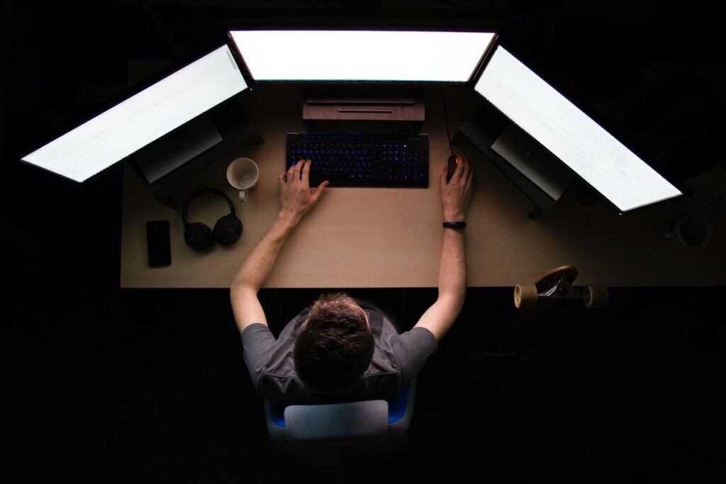 a man works in front of three computer monitors