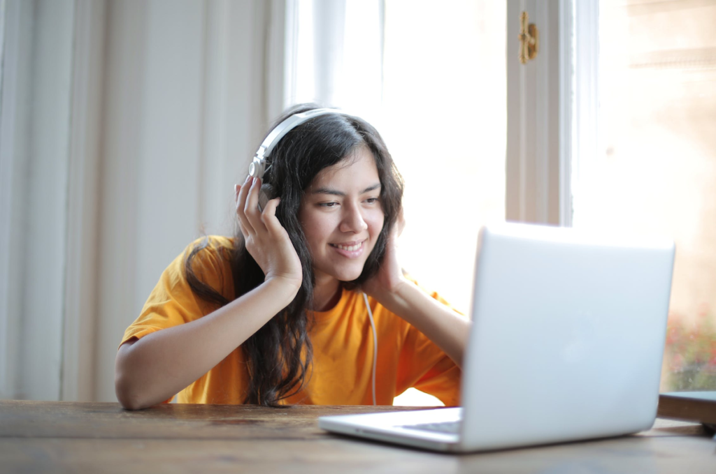 a woman with dark hair smiling while on her laptop