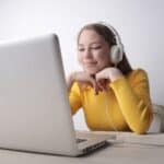 a woman with dark hair smiling while on her laptop