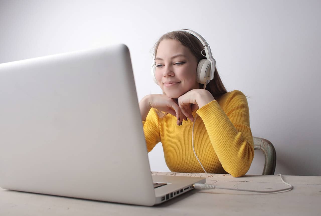 a woman with dark hair smiling while on her laptop