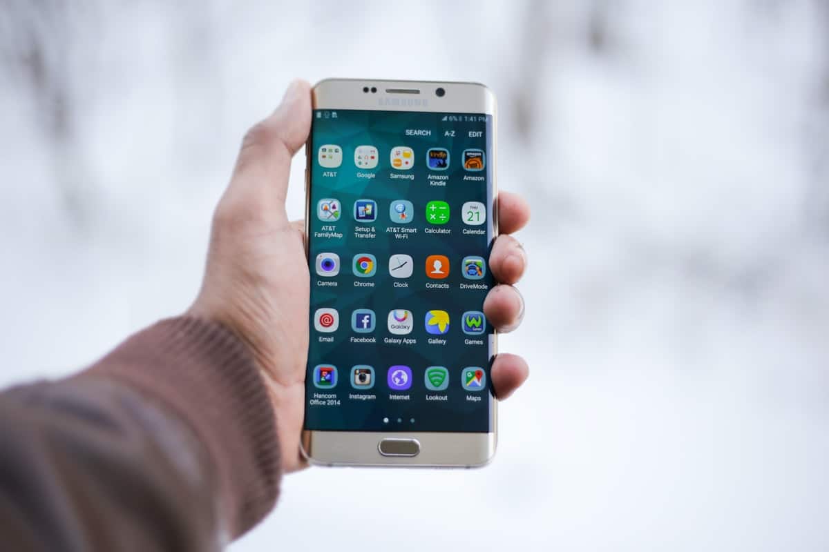 Person holding an Android phone displaying a home screen with app icons. How to Code an App