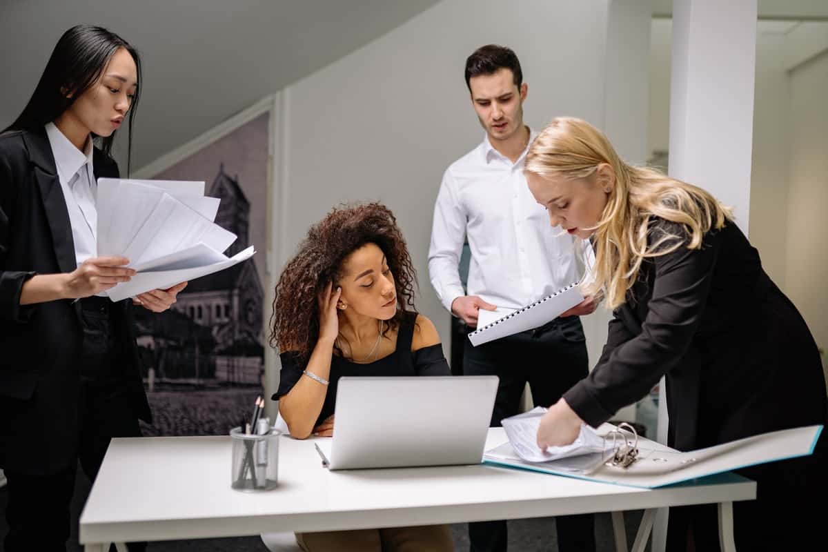 Group of people gathered around a table with a computer and many papers Tips If You Are Considering Dropping Out of College