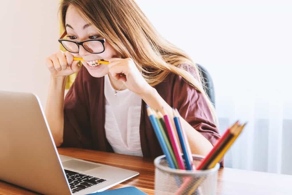 Young woman sitting in front of a computer and biting a pencil Is a Cyber Security Career Right for You?