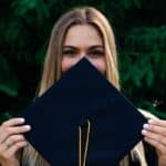 Girl covering her face with a graduation cap Is College for Everyone?