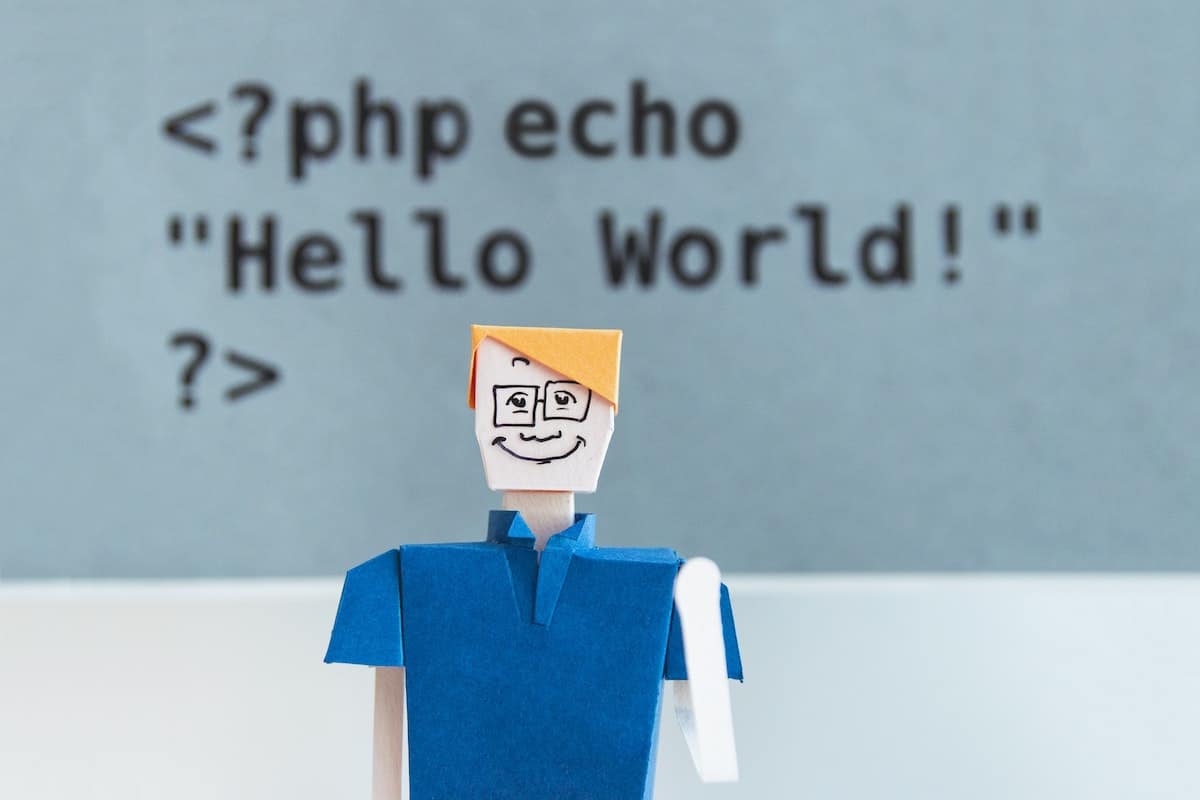 A doll stands in front of a board displaying PHP code. Types of Coding Languages