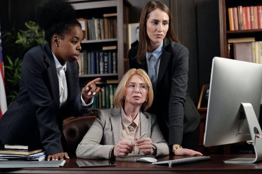 Three women clad in business suits look at a monitor top benefits of business intelligence software