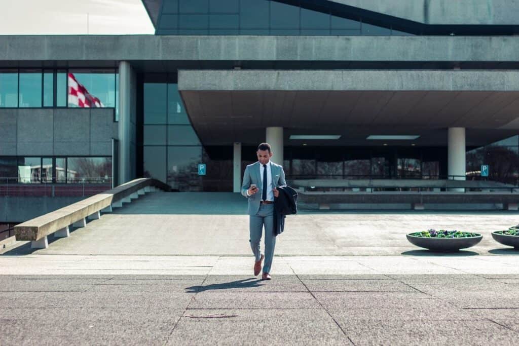 Man in a grey suit walking and using a cellphone with a building in the background how to make a career change