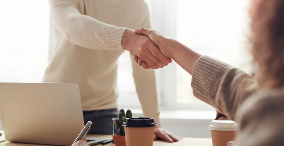 A man shaking a woman’s hand across a table. Applying for a Job at Salesforce: Overview