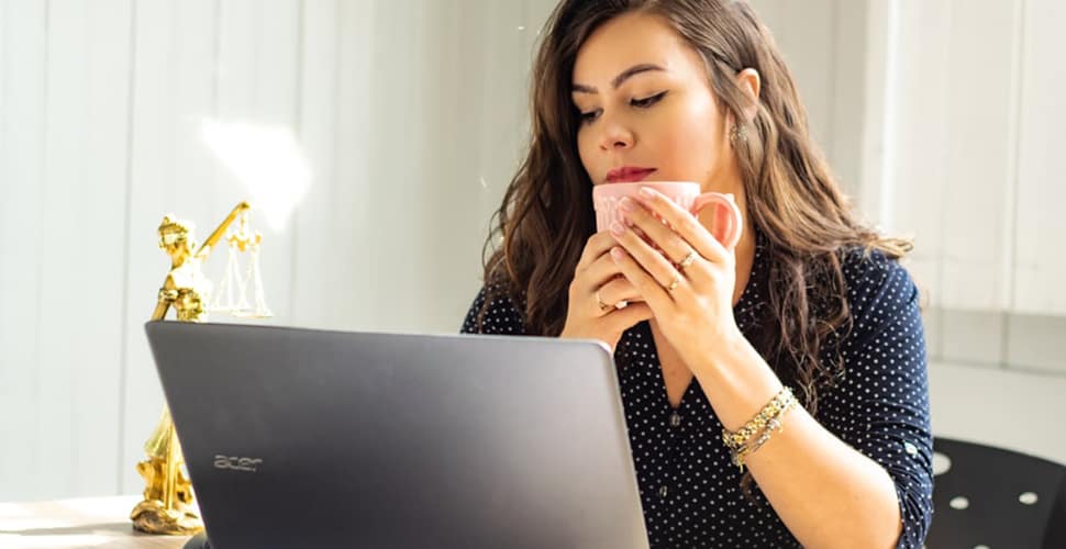 A woman holding a mug and staring at her laptop screen. How to Get a Job at Lockheed Martin