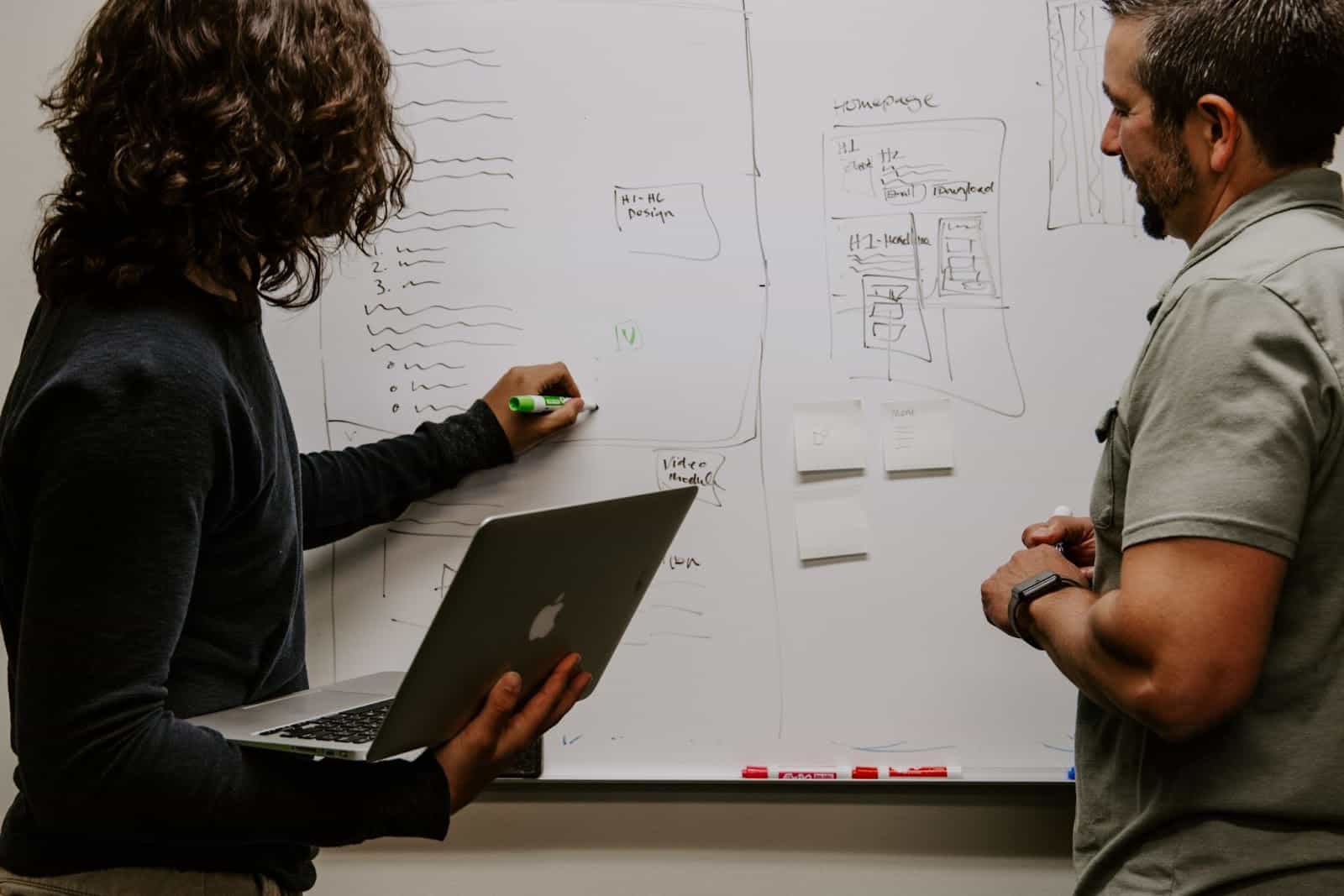 Man wearing gray polo shirt and woman in jacket beside a dry-erase board Data Analytics vs Data Science