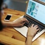 A person reading a newsletter on laptop.